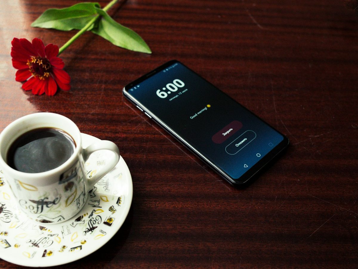 Smartphone und Tasse Kaffee auf einem Holztisch